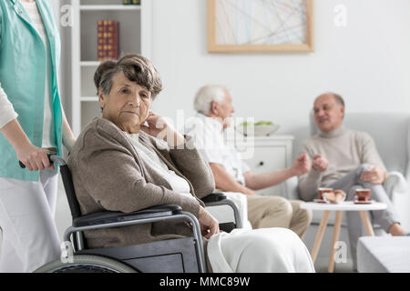 Sconvolto senior donna su una sedia a rotelle in casa di cura Foto Stock