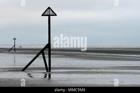 Un trio di lontani gli escursionisti sulla grande spiaggia piana sulla costa ovest WIttering, Sussex England, Regno Unito, bassa marea dall'inverno nuvoloso inglese mare Foto Stock