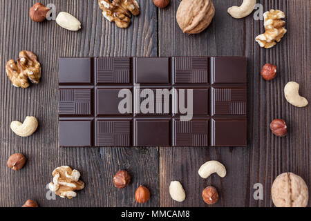Delizioso cioccolato fondente e i dadi su sfondo di legno Foto Stock