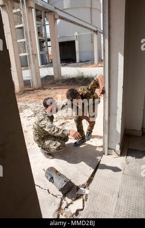 Due siriano Forze Democratiche soldati prendere la copertura dietro un muro e discutere il loro prossimo corso di azione nel corso di un esercizio di formazione per insegnare il rilevamento e l'eliminazione degli ordigni esplosivi artigianali ad Ottobre 9, 2017. Disarmare IED è essenziale per la SDF della missione in luoghi come Raqqah dove i terroristi lasciano dietro di esplosivi di nuocere a liberare le truppe e i civili ritornano alle loro comunità. (US Army photo by Staff Sgt. Richard Lutz) Foto Stock