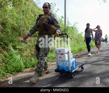 Petty Officer di seconda classe Cruz-Sepulueda Jonathan, un membro della Guardia Costiera porta unità di sicurezza 307, aiuta i residenti il trasporto di acqua e di cibo per la loro casa in Isabela, Puerto Rico, Ott19, 2017. Il personale che opera al di fuori della guardia costiera Stazione aria Borinquen in Aguadilla, Puerto Rico, sono state aiutando consegnare le forniture dalla Federal Emergency Management Agency per aree remote colpiti dall uragano Maria. Stati Uniti Coast Guard foto di Sottufficiali di terza classe David Micallef Foto Stock