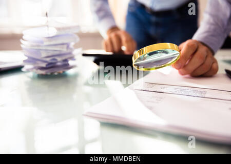 Commercianti la mano analizzando Bill attraverso la lente di ingrandimento Foto Stock
