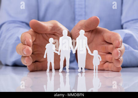 Close-up di un imprenditore la mano della protezione della famiglia figura tagliare Foto Stock