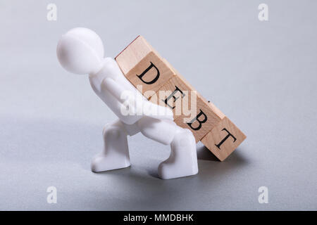 Bianco di Figurine di umani che trasportano il debito dei blocchi di legno su sfondo grigio Foto Stock