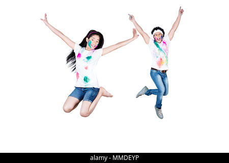 Due Teenage giovane ragazzo e ragazza Jumping divertimento allegro Holi-Celebration Foto Stock