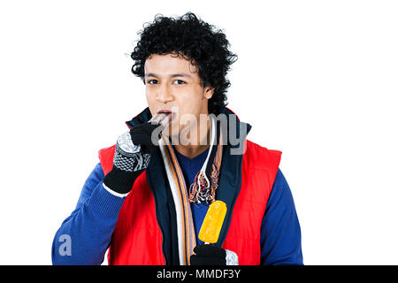 Un giovane uomo abiti In-Winter mangiare deliziosi gelati Winter-Season Foto Stock