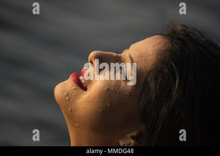 Il profilo laterale di close-up di donna sorridente con la luce del sole sulla faccia Foto Stock