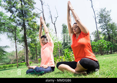 Due coniugi a praticare Yoga Surya-Namaskar meditando In-Park allenamento Foto Stock