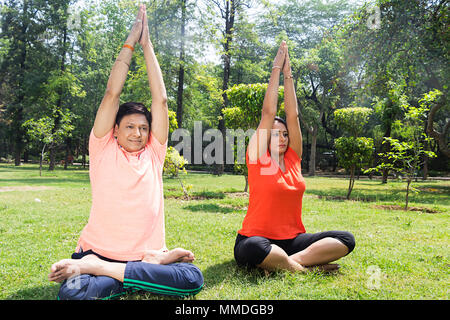 Due coppie di idoneità esercizio di meditazione Yoga Surya Namaskar in giardino Foto Stock