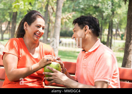 Due giovane seduto al banco di bere acqua di cocco divertente allegro In-Park Foto Stock