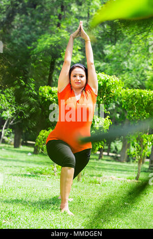 Una donna Stretching fare yoga Surya-Namaskar meditando esercizio fitness Giardino Foto Stock