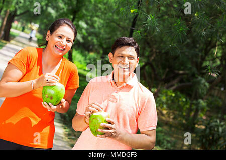 Felice l'uomo, donna giovane di bere acqua di cocco rinfrescante In-Park Morning-Walk Foto Stock