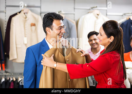 Married-Couple selezionando un cappotto mentre lo shopping per i vestiti nel negozio di abbigliamento Foto Stock