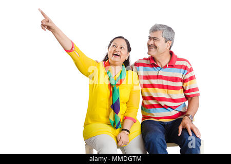 Coppia senior seduti insieme puntando il dito che mostra Happy Fun Allegro Foto Stock