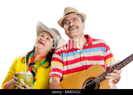 Felice Coppia senior a suonare la chitarra sing-song con noce di cocco : acqua avente Fun Foto Stock