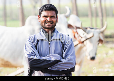 L'agricoltore rurale Crossed-Arms campo permanente di lavoro di villaggio nei pressi di animali Foto Stock