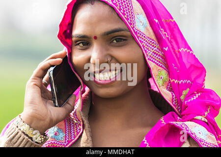 Uno rurale indiano femmina abitante parlando su Mobile-Phone villaggio all'aperto Foto Stock