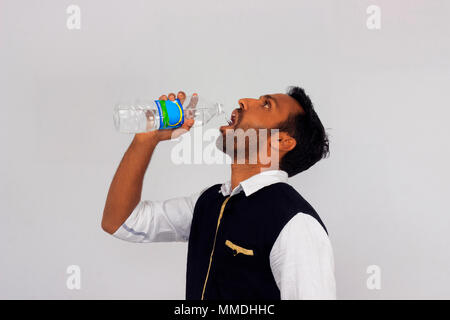 Giovane uomo in India abbigliamento acqua potabile da una bottiglia Foto Stock