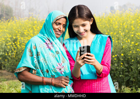 Rural madre e figlia Text-Messaging lettura Cellulare Field-Village Foto Stock