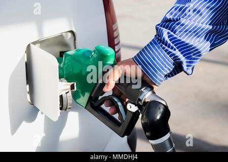 I dipendenti di sesso maschile comandata la pompa del carburante con carburante ugelli aggiungendo benzina in auto Foto Stock