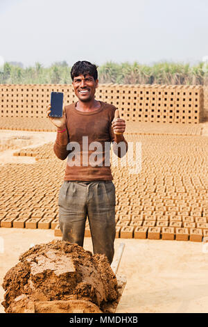 Un lavoro che mostra maschio pollice in su con il cellulare In-Village Brick-Factory Foto Stock