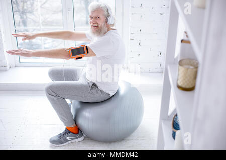 Anziani uomo sorridente mentre ascolti la musica e di esercizio Foto Stock