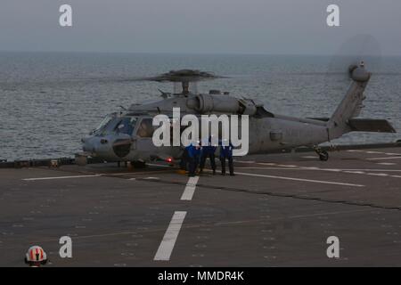 I marinai di supportare un MH-60 Seahawk elicottero a bordo della USS Lewis B. estrattore durante il touch-e-go air operations ott. 18, 2017. USS estrattore supporta Naval Amphibious vigore, Task Force 51/5th Marine Expeditionary Brigade diverse missioni che includono la risposta alle crisi, airborne miniera contromisure contro la pirateria operazioni, le operazioni di sicurezza marittima e di aiuti umanitari/Disaster Relief missioni mentre in avanti distribuito negli Stati Uniti Quinta Flotta area di operazioni. (U.S. Marine Corps Foto di Cpl. Jessica Y. Lucio) Foto Stock