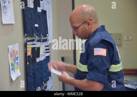 Stati Uniti Coast Guard Chief Petty Officer Irwin Pascal, l'unità di risorse leader, controlli nei pazienti responsivi all'uragano Maria FSE-10 PR comando unificato Incident Command Post in San Juan, Puerto Rico, 20 ott. 2017. La Maria FSE-10 PR comando unificato, consistente del dipartimento delle risorse naturali e ambientali, U.S. Coast Guard in congiunzione con il Porto Rico della qualità ambientale Scheda di controllo, Agenzia di protezione ambientale e di Stati Uniti e Fish & Wildlife Service, risponde alle navi trovato essere danneggiato, spostato, sommerse o affondata. Il FSE 10 è il quadro con il Foto Stock