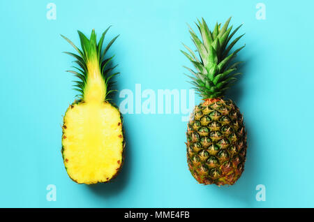 Ananas intero e metà frutta tagliata su sfondo blu. Vista dall'alto. Copia dello spazio. Ananassi luminoso modello per stile minimal. Pop art design, creative Foto Stock