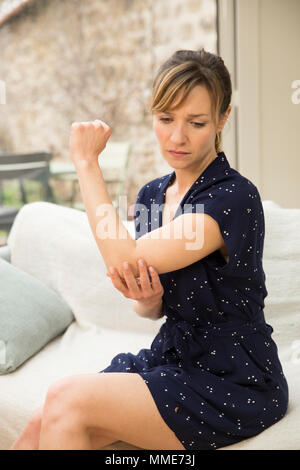 Donna con gomito doloroso Foto Stock