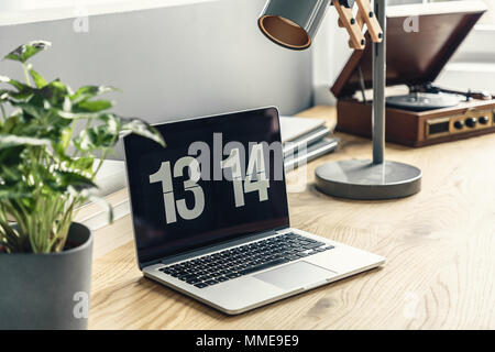 Portatile su una scrivania in legno, impianto, lampada e una vendemmia record giocatore in uno spazio di lavoro di un luminoso, hipster living room interior Foto Stock