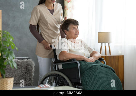 Signora senior con la malattia di Alzheimer, seduto in una sedia a rotelle, confusi su dove ella è Foto Stock