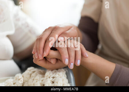 Close-up foto di una femmina di caregiver e senior donna tenendo le mani. Senior il concetto di cura. Foto Stock