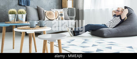 Vista panoramica di un giovane uomo rilassante in un sacco di seduta in un moderno appartamento studio Foto Stock