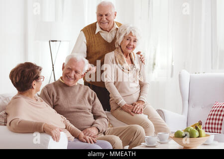 Due coppie senior rilassante insieme a casa e parlando e sorridente Foto Stock