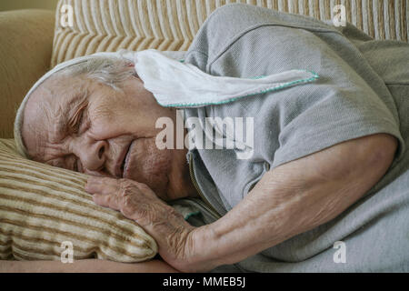 Un senior donna sonnecchiare sul divano Foto Stock