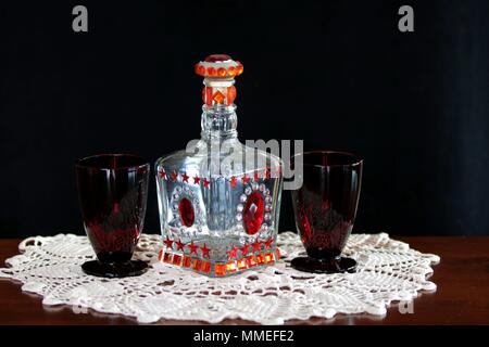 Vaso decorativo e rosso rubino occhiali antichi su un antico uncinetto centrino Foto Stock