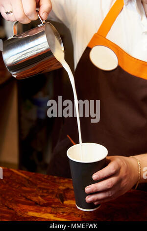 Barista prepara una bevanda di caffè dietro un contatore di legno. Foto Stock