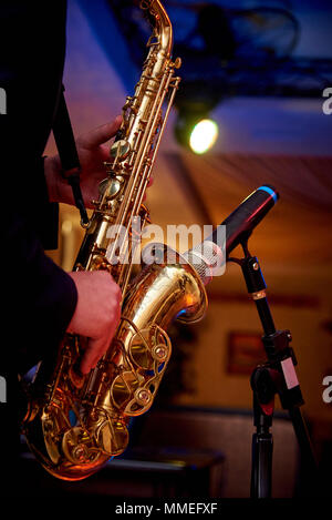 Un Dorato sassofono nelle mani di un musicista in prossimità del microfono sul contatore Foto Stock