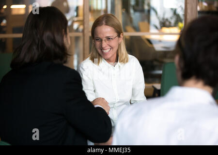 Sorridente imprenditrice agitando la mano dell'uomo d'affari di mediazione Foto Stock