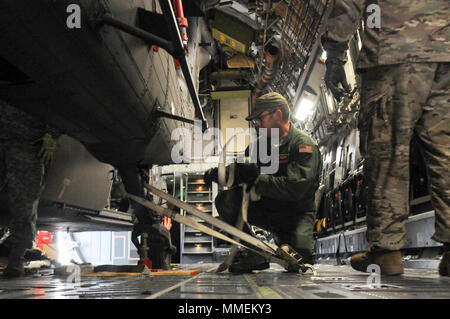 Un loadmaster con il Tennessee Guardia Nazionale di 164Airlift Wing assicura un UH-60 Black Hawk elicottero all'interno di un C-17 Globemaster III ott. 26, 2017 a Rickenbacker Air National Guard Base in Columbus, Ohio. L'elicottero e equipaggio dal 1° Battaglione, 137Reggimento aviazione stanno distribuendo a Puerto Rico per assistere nelle operazioni di recupero dopo il passaggio dell uragano Maria. (Ohio Guardia Nazionale foto di 1Lt. Jordyn Sadowski) Foto Stock