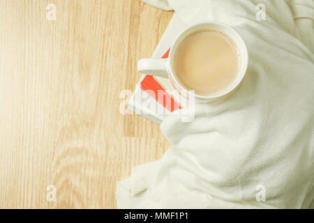 Tazza di caffè, panno bianco e la pila di libri sulla sommità di uno sfondo di legno. La colazione del mattino. Vista dall'alto. Foto Stock
