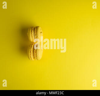 Due macarons giallo su sfondo giallo, vista dall'alto, spazio di copia Foto Stock