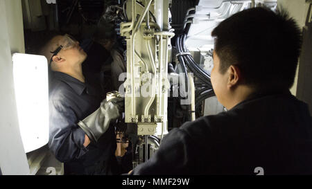 Oceano Pacifico (nov. 7, 2017) Gunners Mate marinaio Jacob Bartolome osserva come Gunners Mate marinaio Dylan Weisert esegue le operazioni di manutenzione su un Mk 45 5 pollici pistola a bordo Ticonderoga-class guidato-missili cruiser USS Lake Champlain (CG 57). Lake Champlain sta partecipando a un supporto esercitazione in preparazione per una prossima distribuzione. (U.S. Foto di Marina di Massa Specialista comunicazione prima classe Nathan Carpenter/rilasciato) Foto Stock