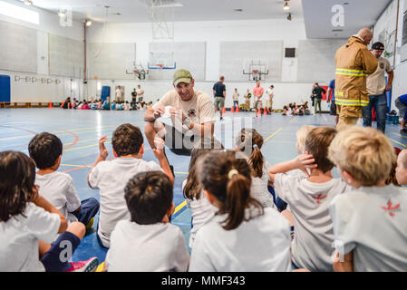 Un vigile del fuoco assegnato al 379 Expeditionary ingegnere civile Squadron insegna ai bambini circa i rilevatori di fumo durante una presentazione sulla sicurezza antincendio presso la scuola americana di Doha, in Qatar, 11 ott. 2017. I bambini hanno avuto la possibilità di svolgere esercitazioni, provare le attrezzature antincendio e di soddisfare Sparky il fuoco cane. L evento è stato parte di prevenzione di incendi settimana, ospitato da 379 ECES. (U.S. Air National Guard foto di Tech. Sgt. Bradly A. Schneider/rilasciato) Foto Stock