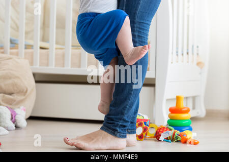 Primo piano immagine di barefoot toddler boy salendo sulla madre Foto Stock