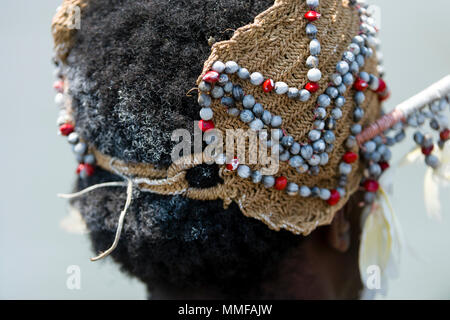 Un Asmat warrior indossando un copricapo tessuti decorati con conchiglie e piume. Foto Stock