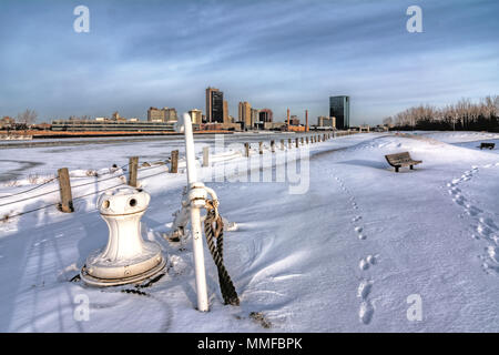 Una vista del centro della città di Toledo Ohio sullo skyline di tutto il congelato e coperto di neve Fiume Maumee. Una nave di ancoraggio può essere visto in primo piano. Foto Stock