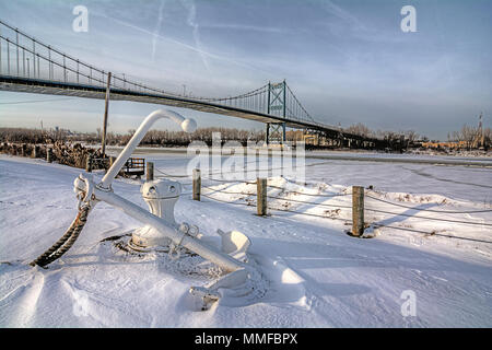 Vista del centro della città di Toledo Ohio è di alto livello per il ponte di sospensione come esso attraversa il congelato Fiume Maumee. Una vecchia nave ancoraggio è visibile in primo piano. Foto Stock