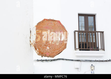 LANZAROTE, Isole canarie, Spagna, Europa: vecchio arrugginito e alterò il segnale di arresto su una parete bianca con un piccolo balcone in background. Foto Stock